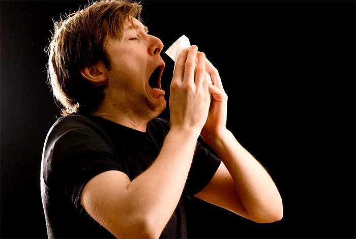 Photo di un uomo che starnutisce a proposito delle origini dell'espressione 'God bless you' in inglese.